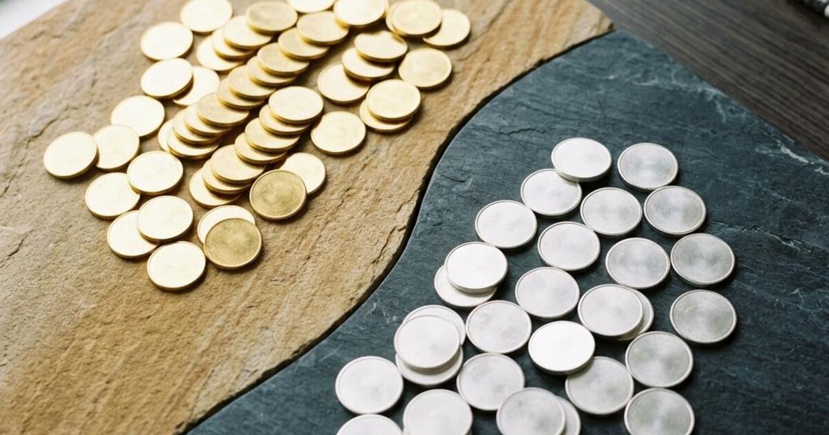 Concept illustration contrasting plain gold bullion discs on beige stone with silver discs on charcoal stone